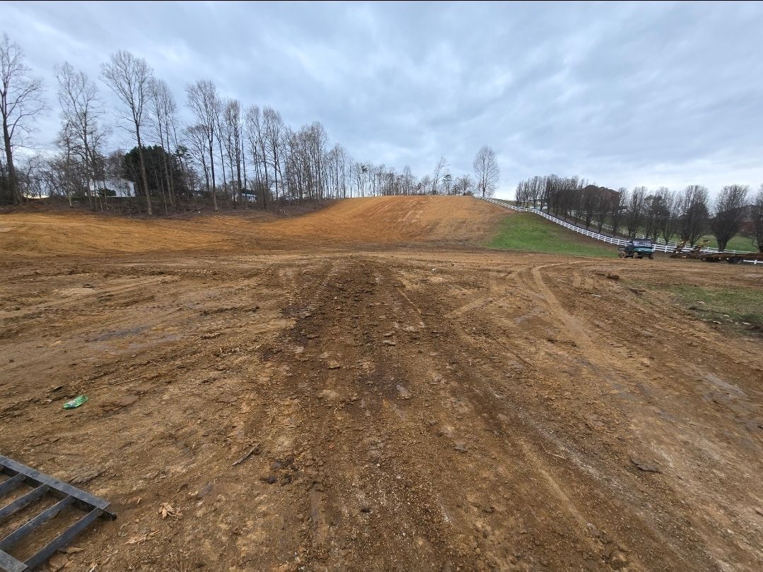 A dirt road with a hill in the background and trees in the background.