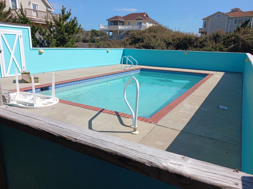 Outdoor swimming pool with blue water, diving board, and turquoise walls on a sunny day