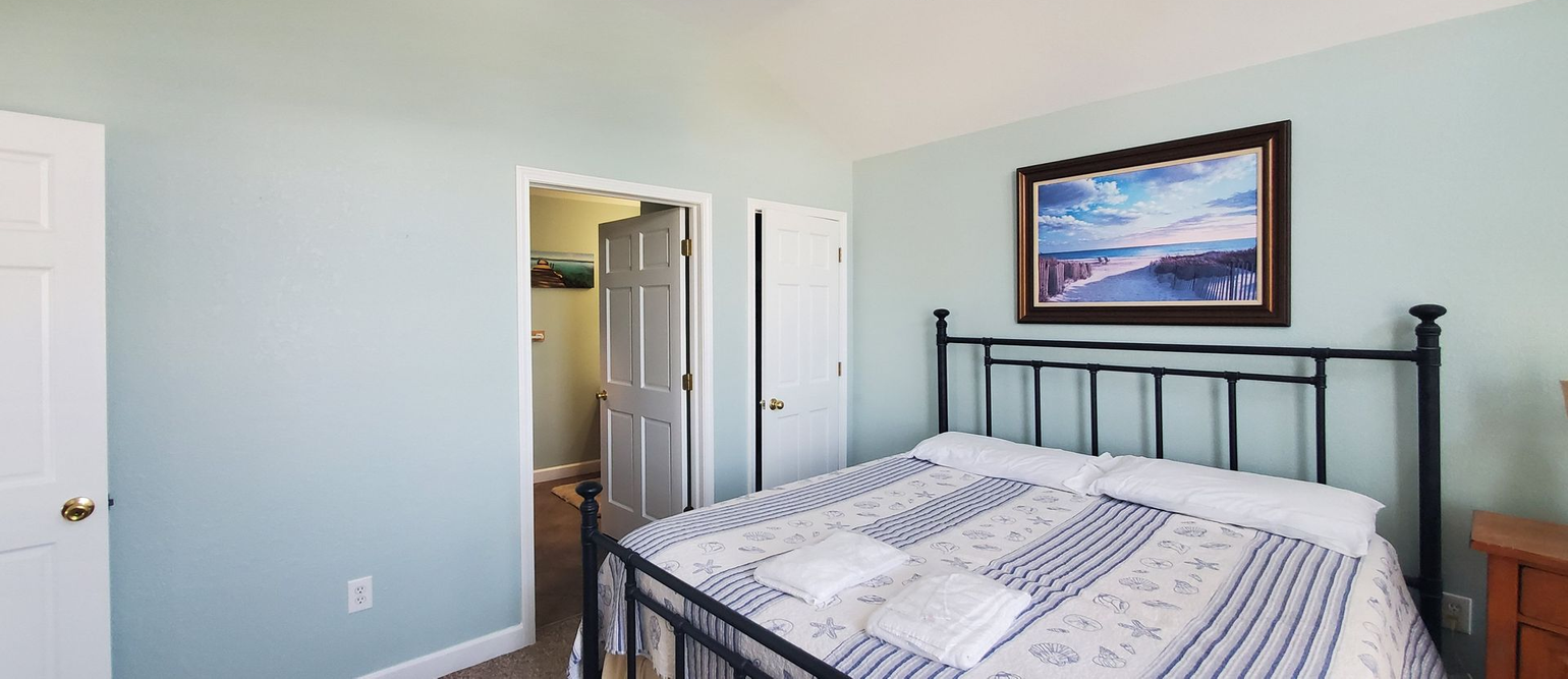 Bedroom with a black metal bed, patterned bedding, wall art, and an open closet door