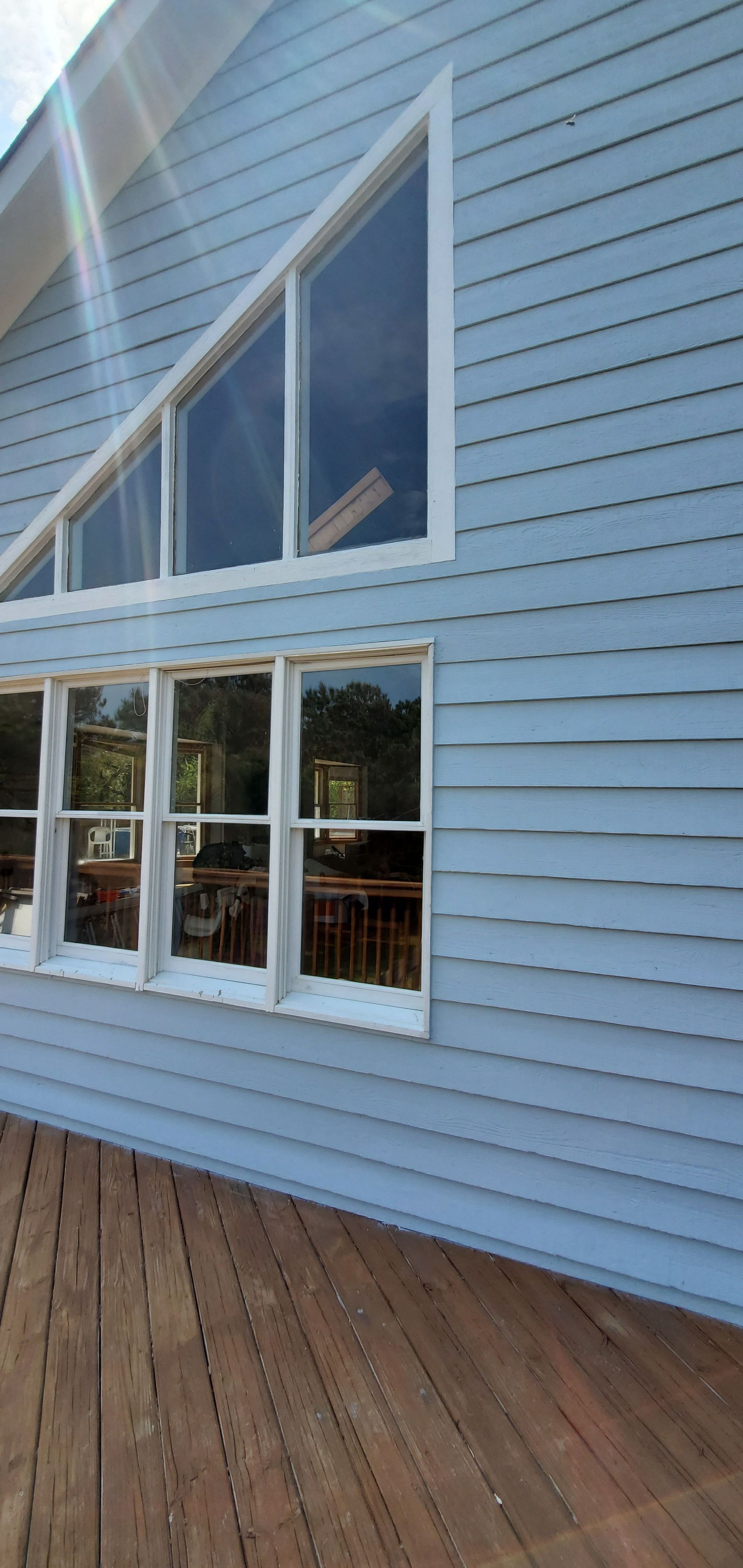 Blue-sided building with white-trimmed windows and a wooden deck in front