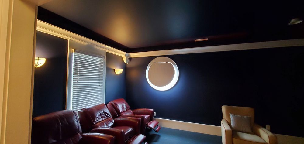 Dark navy living room with leather sofa, round wall mirror, and window blinds on the left