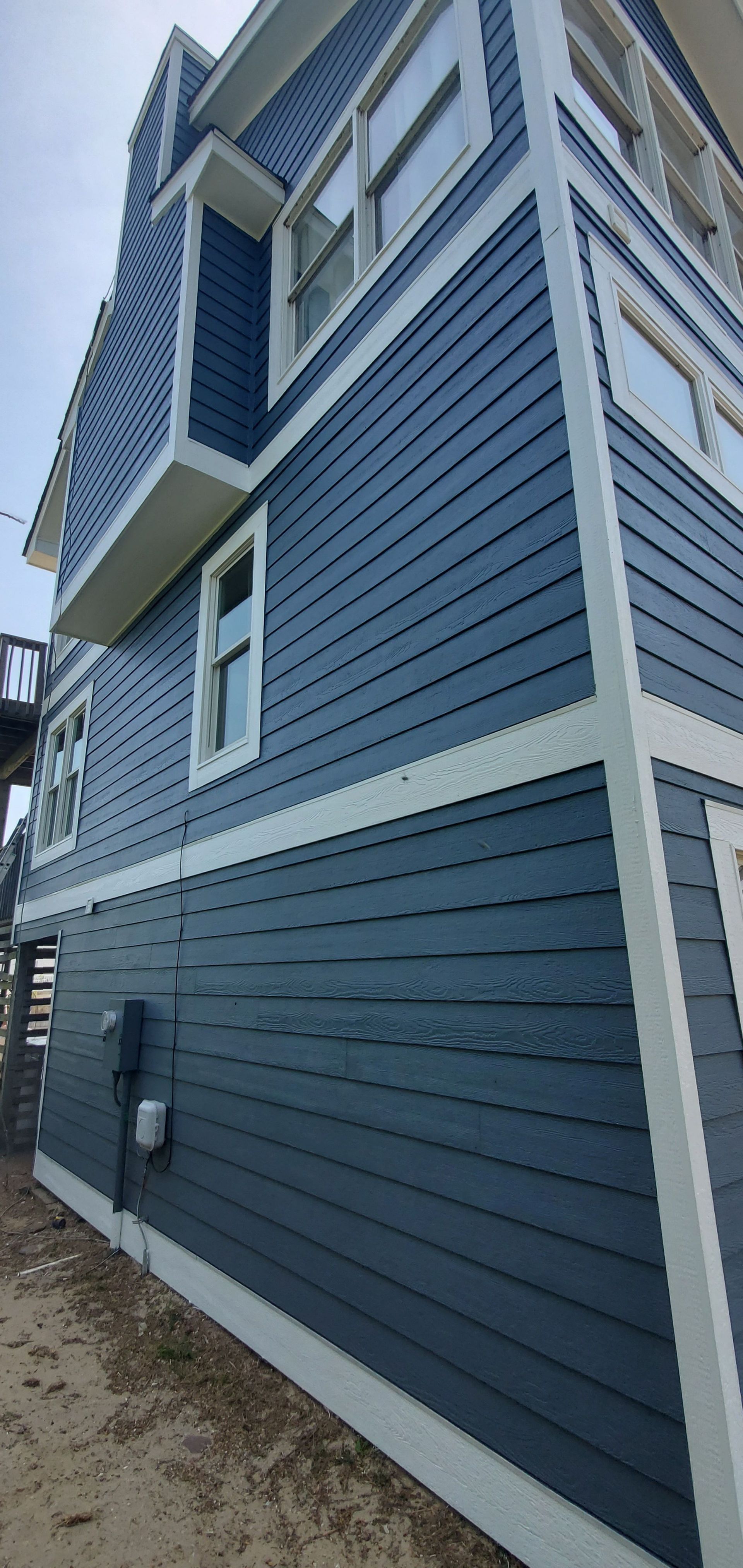 Blue-and-white multi-story house exterior with siding and narrow side yard