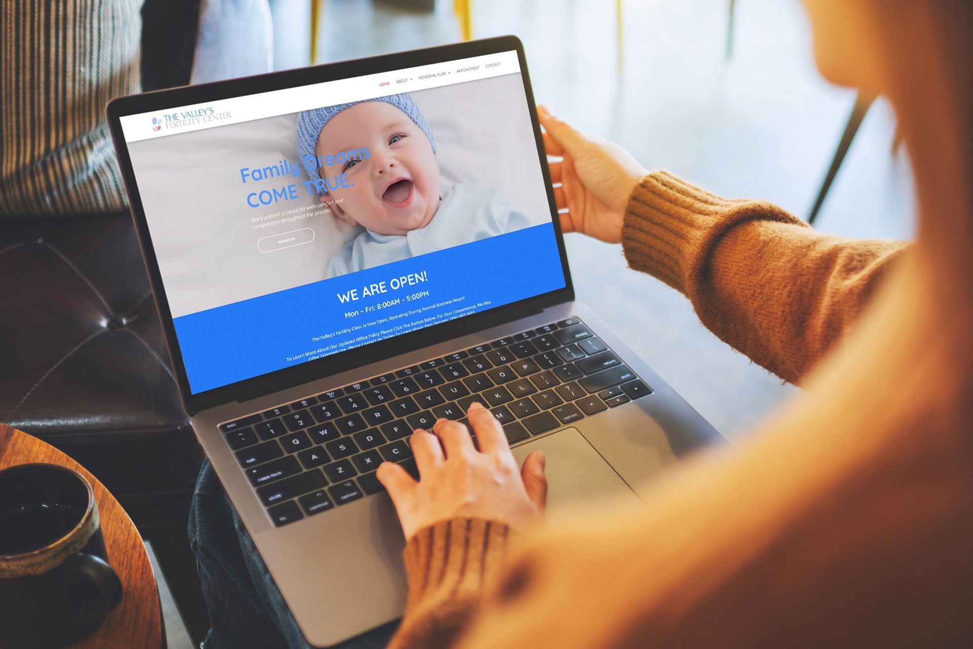 A woman is typing on a laptop computer with a picture of a baby on the screen.