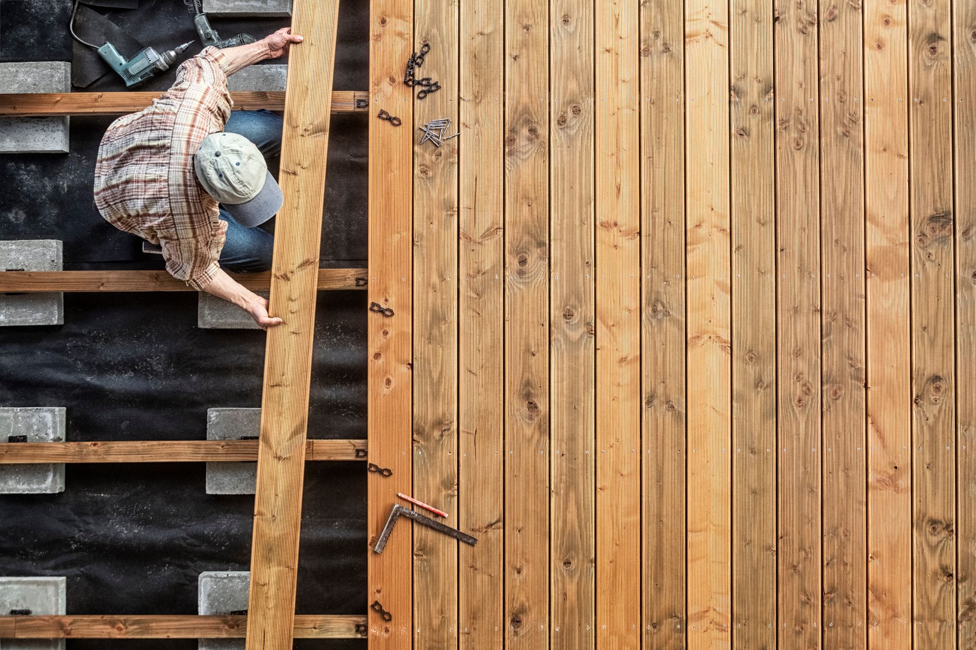 Person installing wooden planks to build an outdoor deck.