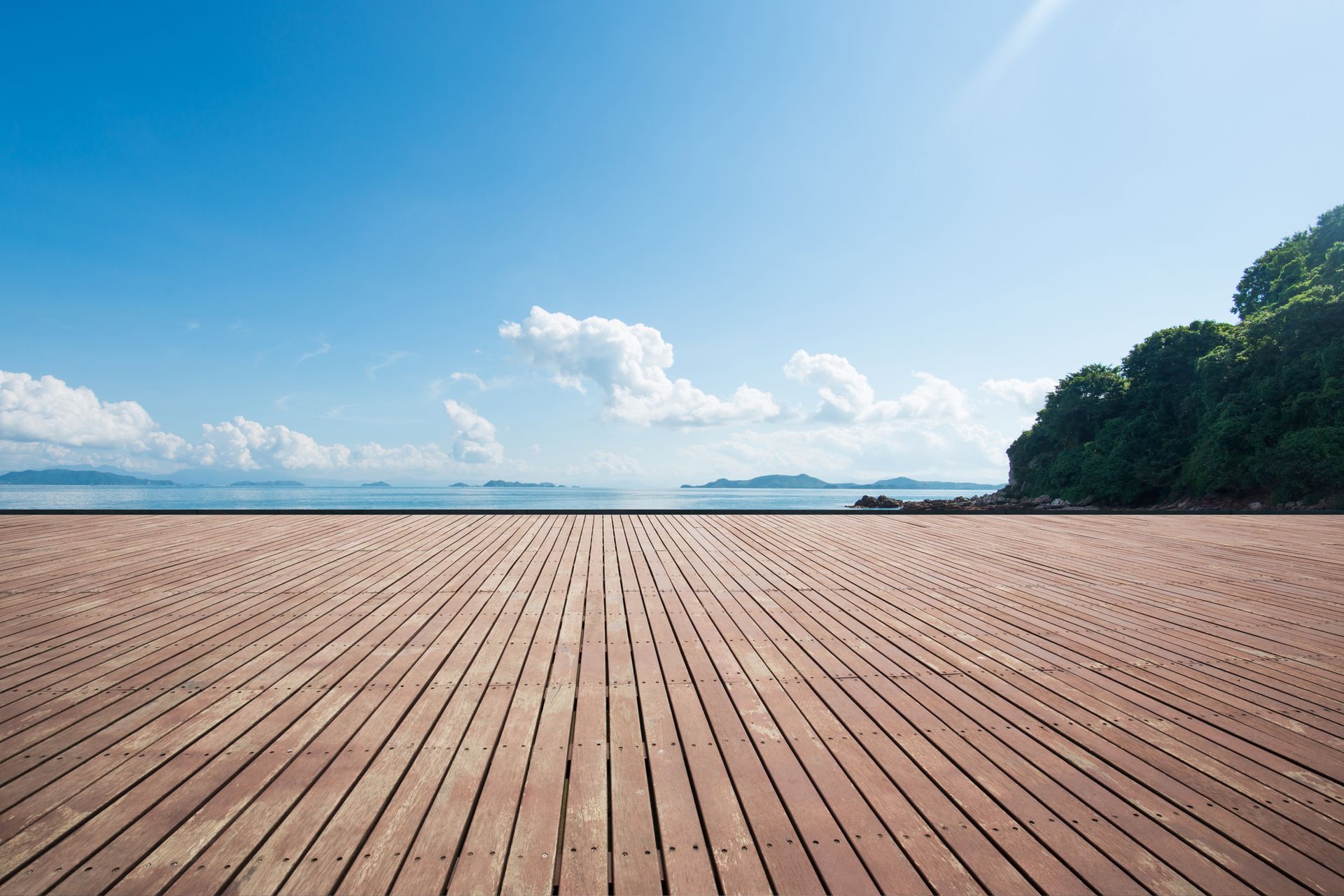 Wooden floor with blue sky and ocean, ideal for showcasing decking supplies in a coastal setting.