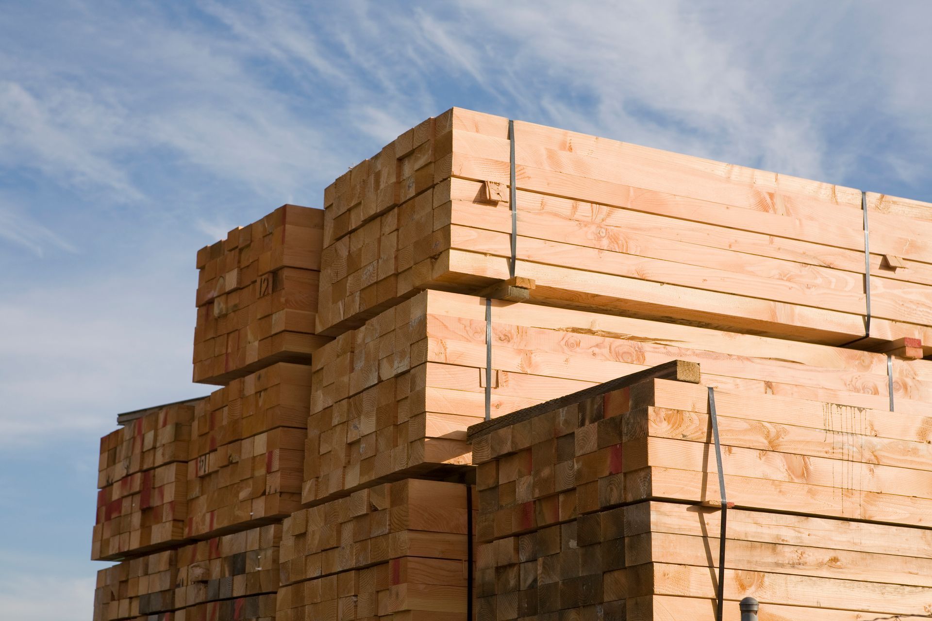 Stacks of lumber under a blue sky.