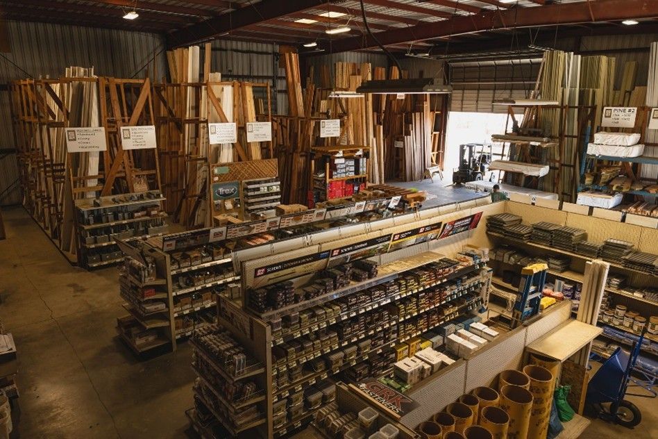 A lumber yard warehouse with stacked wood planks, hardware aisles, and construction supplies