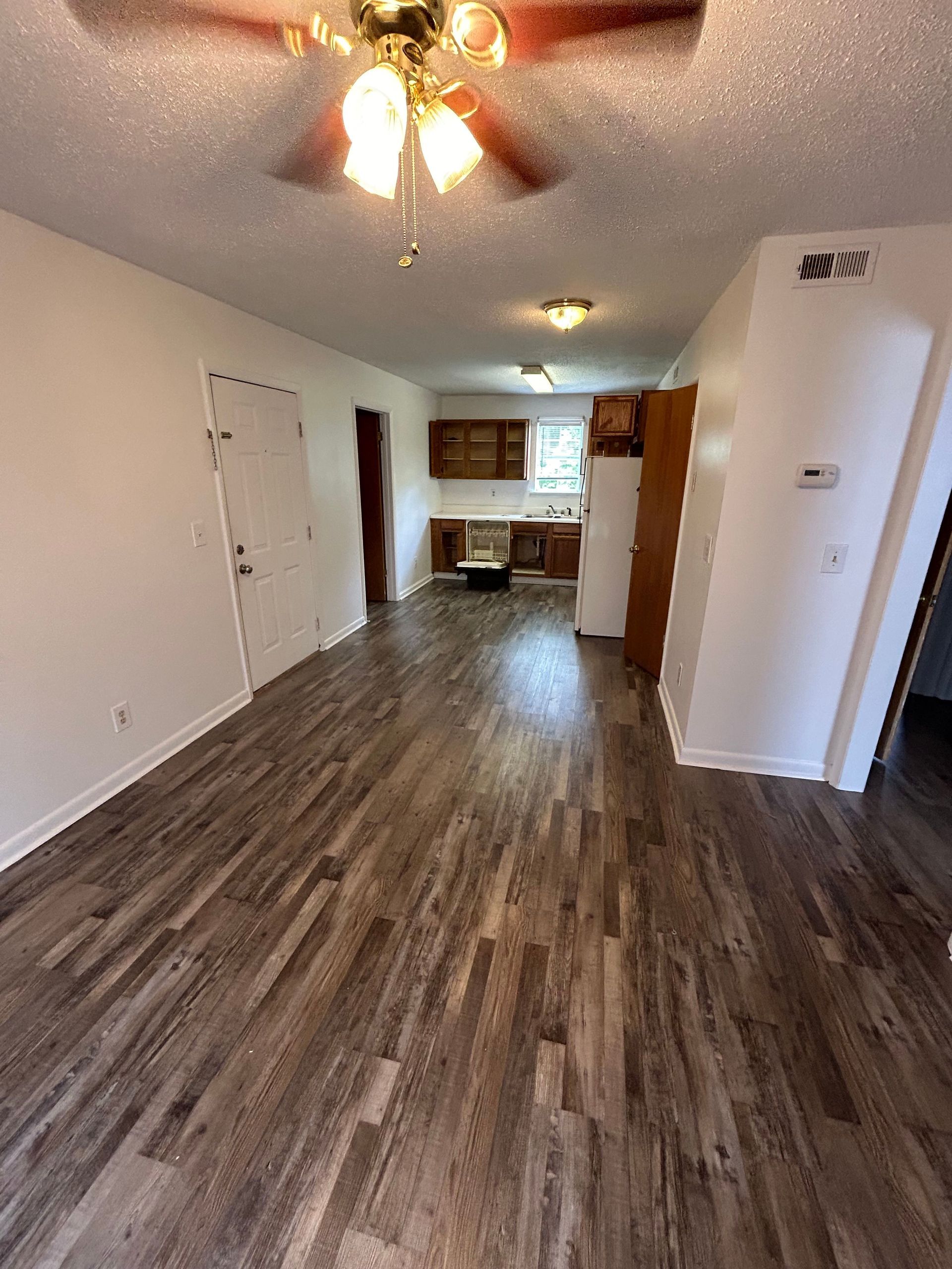 A living room with hardwood floors and a ceiling fan.