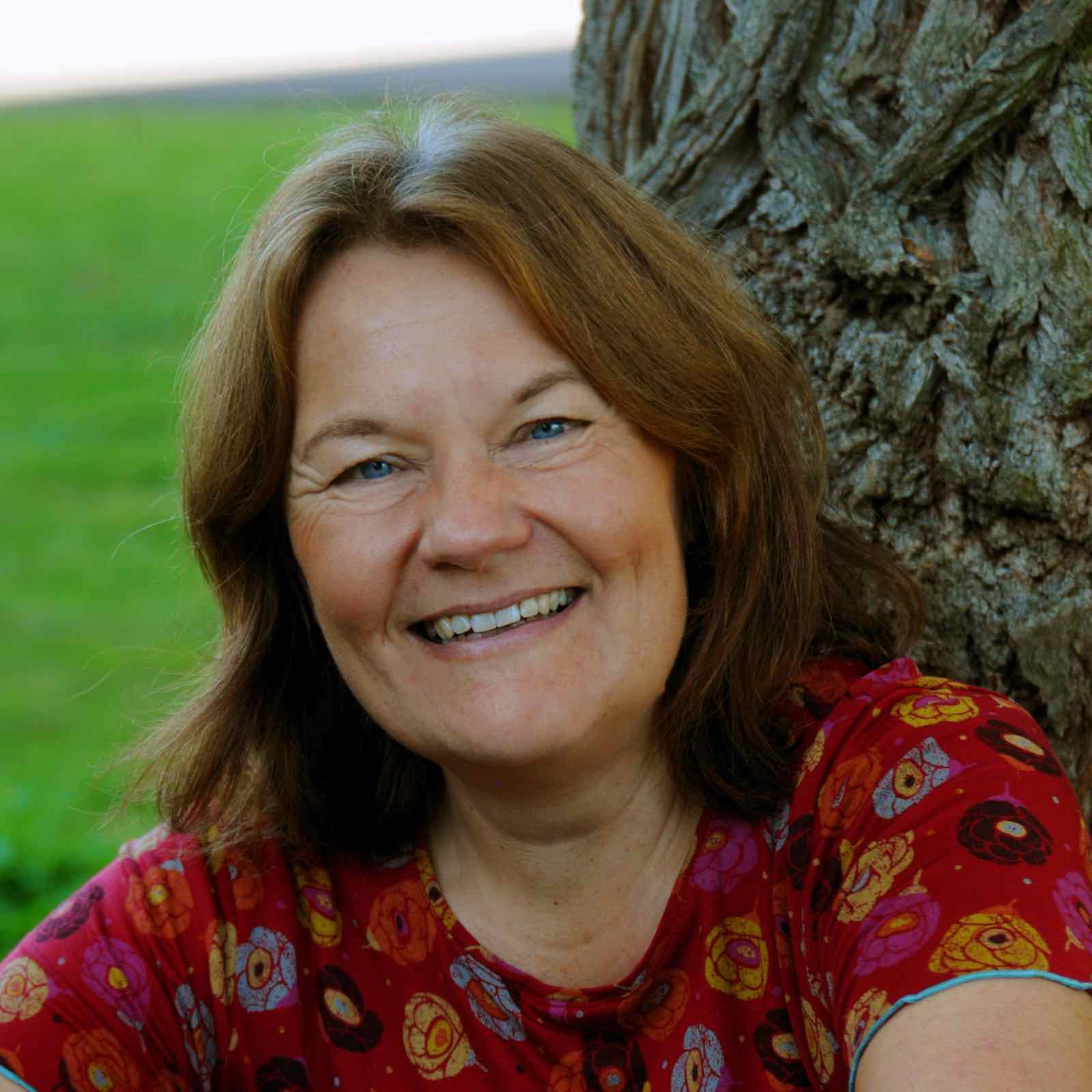 Porträtbild von Tanja Dränert in der Natur an einen Baumstamm gelehnt.