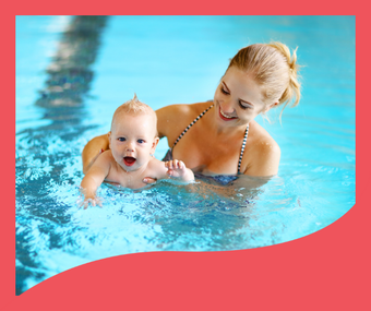 A woman is holding a baby in a swimming pool.