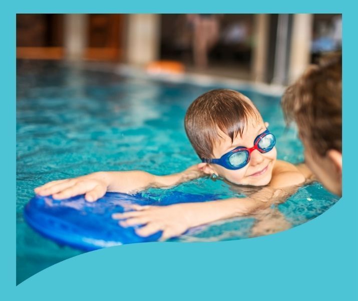A young boy wearing goggles is swimming in a pool.
