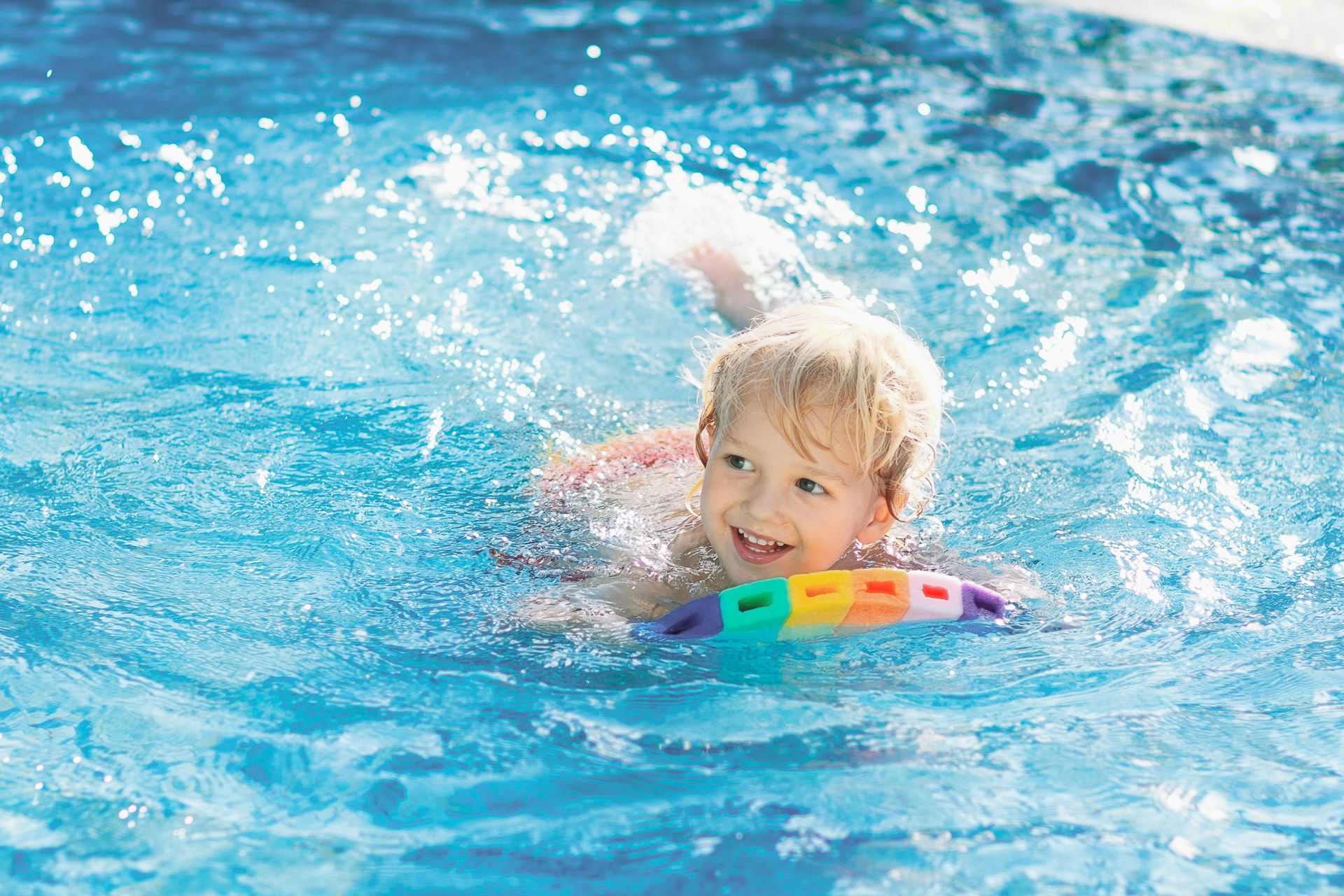 A little boy is swimming in a swimming pool with a float.
