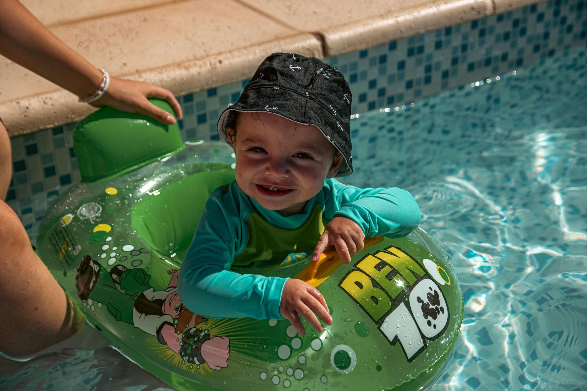 A baby is sitting in a ben 10 float in a pool.