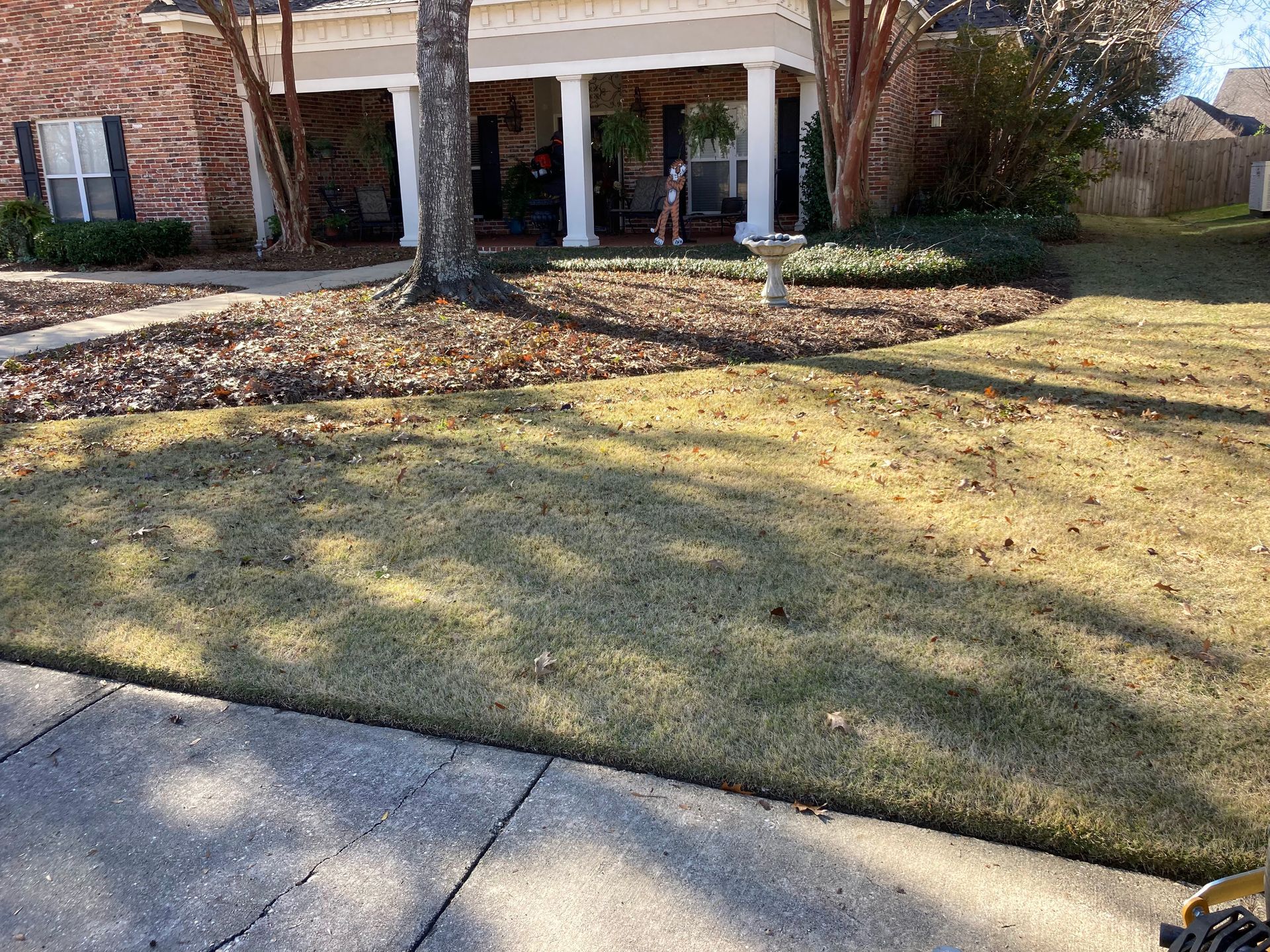 A lawn mower is sitting on the sidewalk in front of a house.