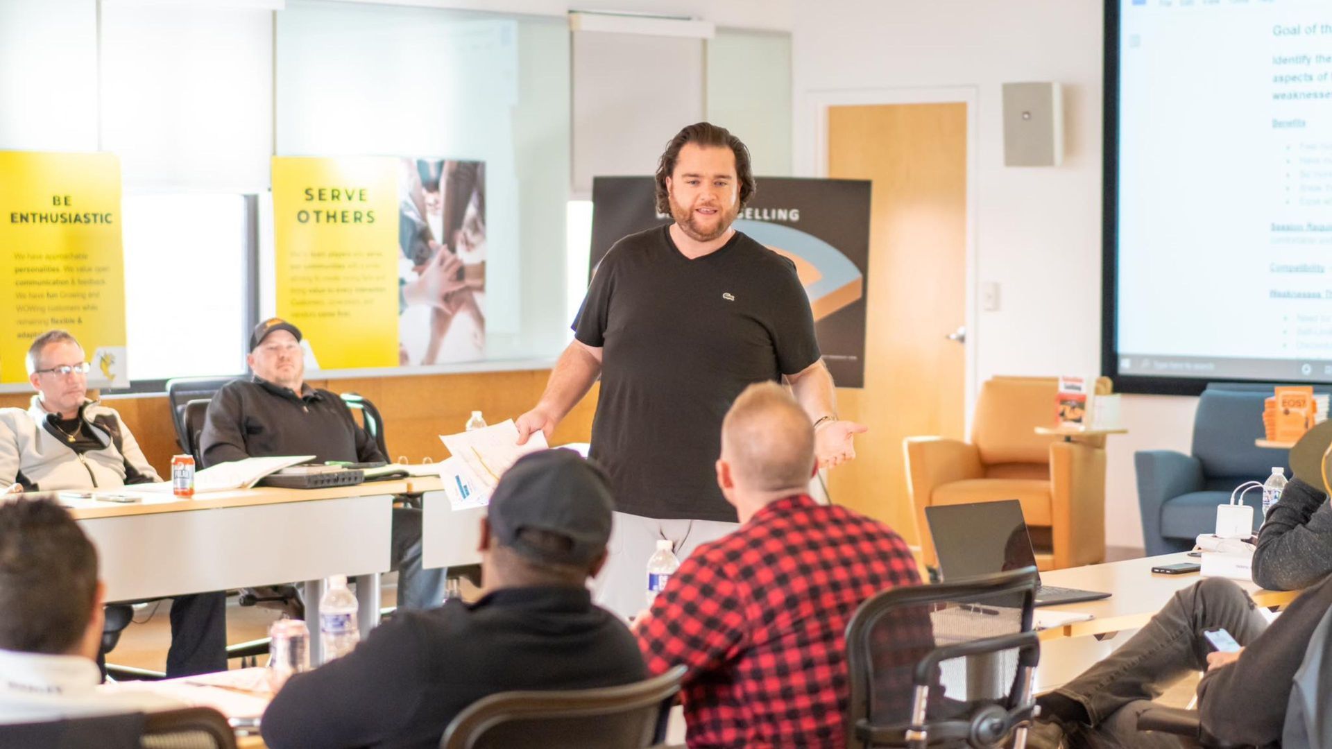A man is giving a presentation to a group of people in a classroom.