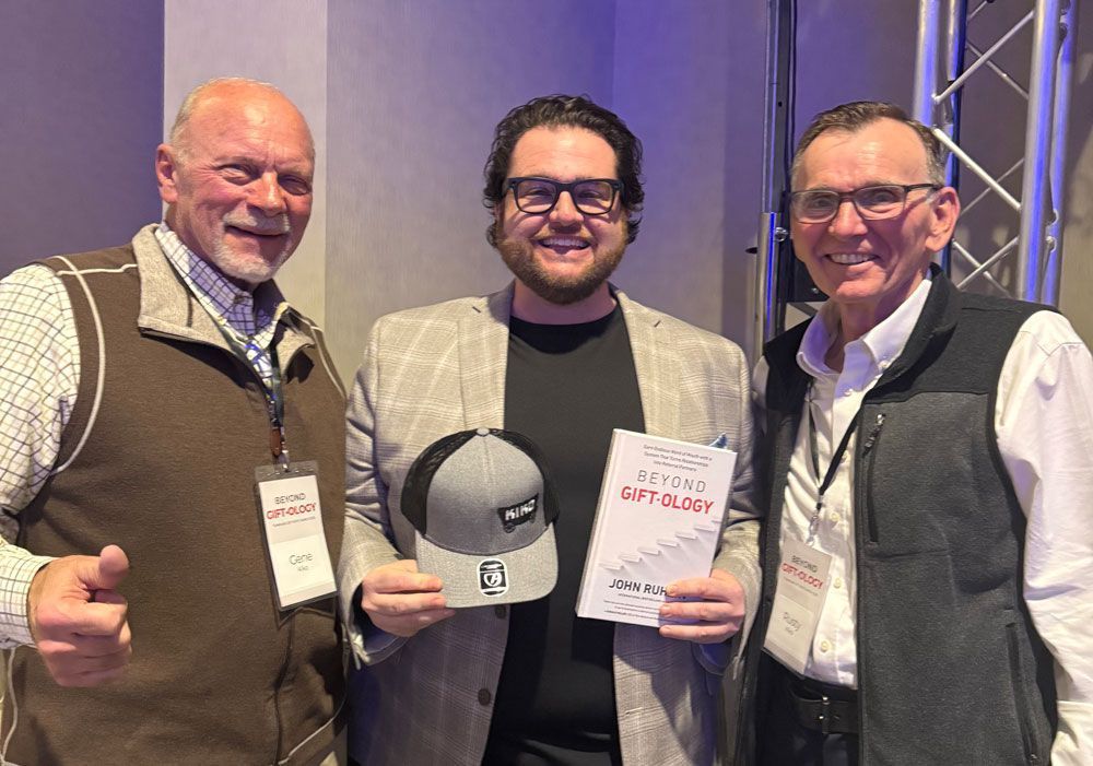 Three men are standing next to each other holding a hat and a book.