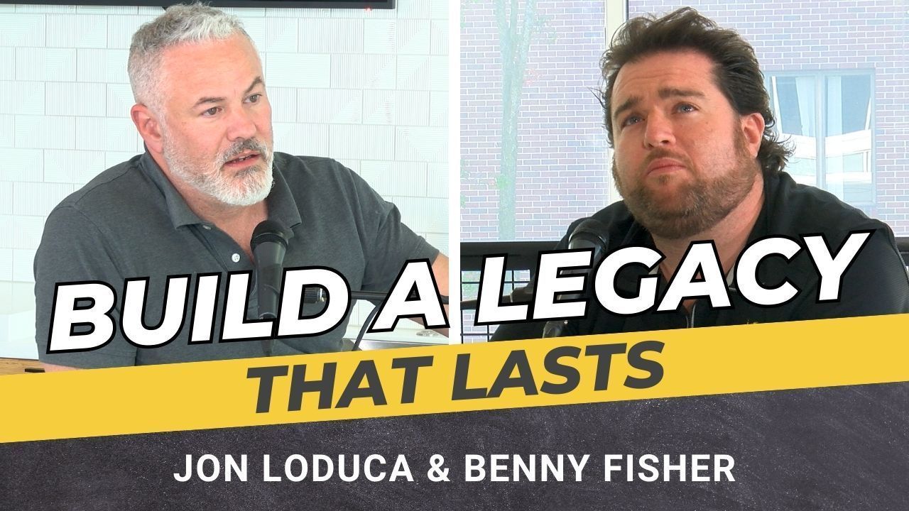 Two men are sitting next to each other in front of a sign that says build a legacy that lasts.