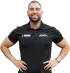 A man with a beard is wearing a black polo shirt and a watch.