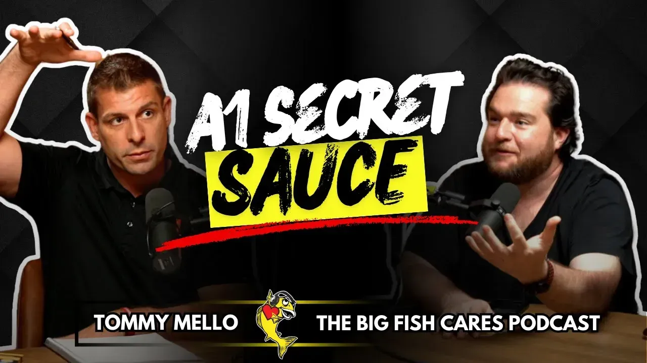 Two men are sitting at a table with microphones in front of a sign that says a1 secret sauce