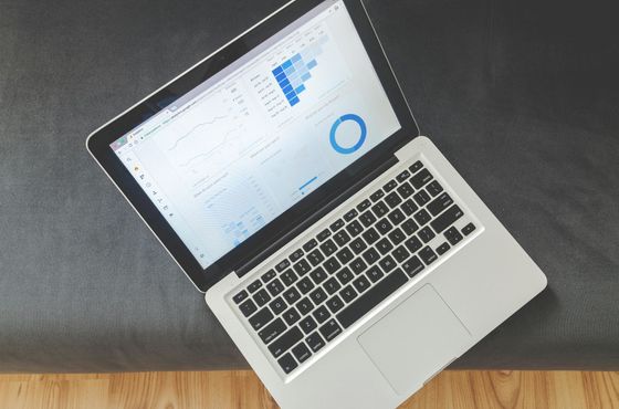 An open laptop with blue analytics pictures on it
