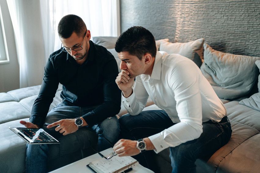 Two men looking at a tablet and thinking
