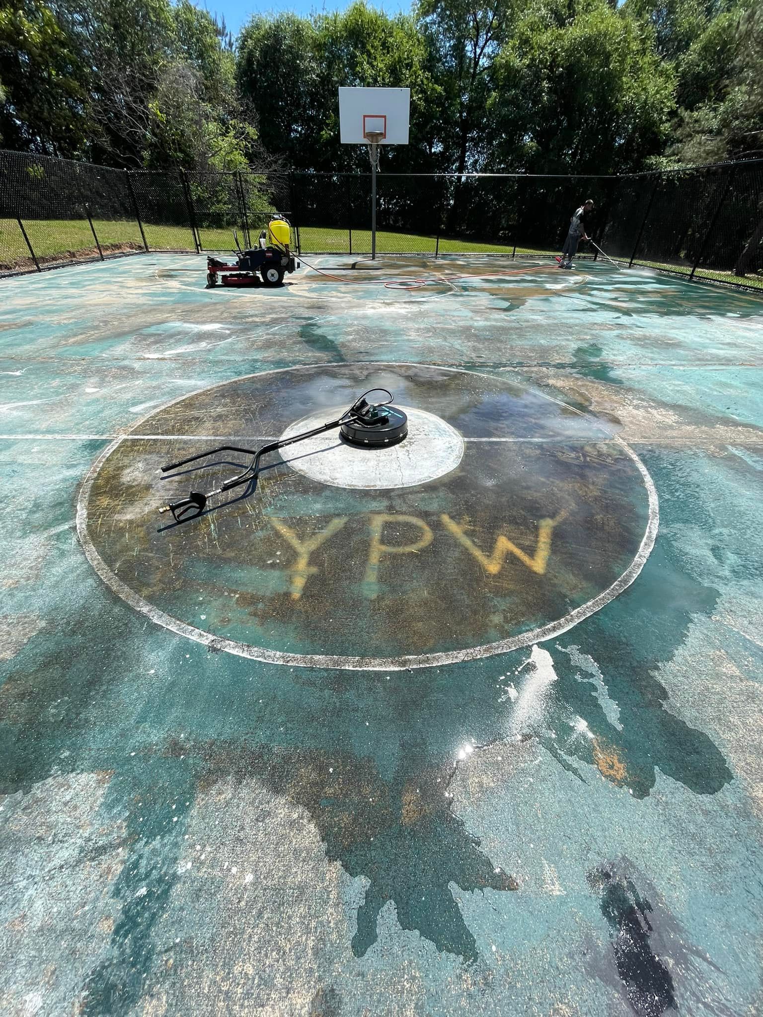 Outdoor basketball court with a faded circle and YPW letters on the painted surface.