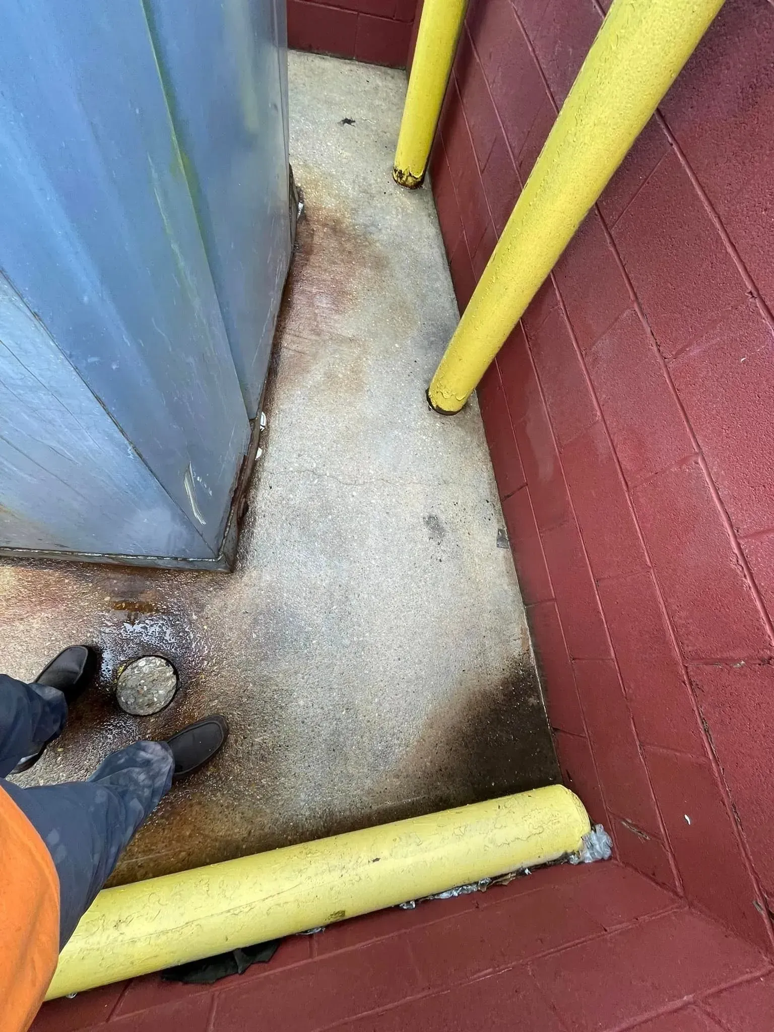 Person's feet near a steel structure and red wall. Yellow bumpers protect the corners.