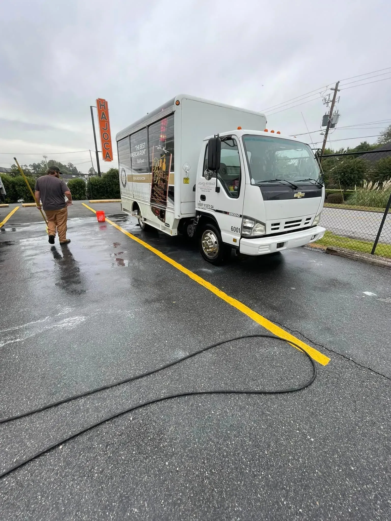 White commercial truck parked on wet asphalt, person walks away, yellow line.