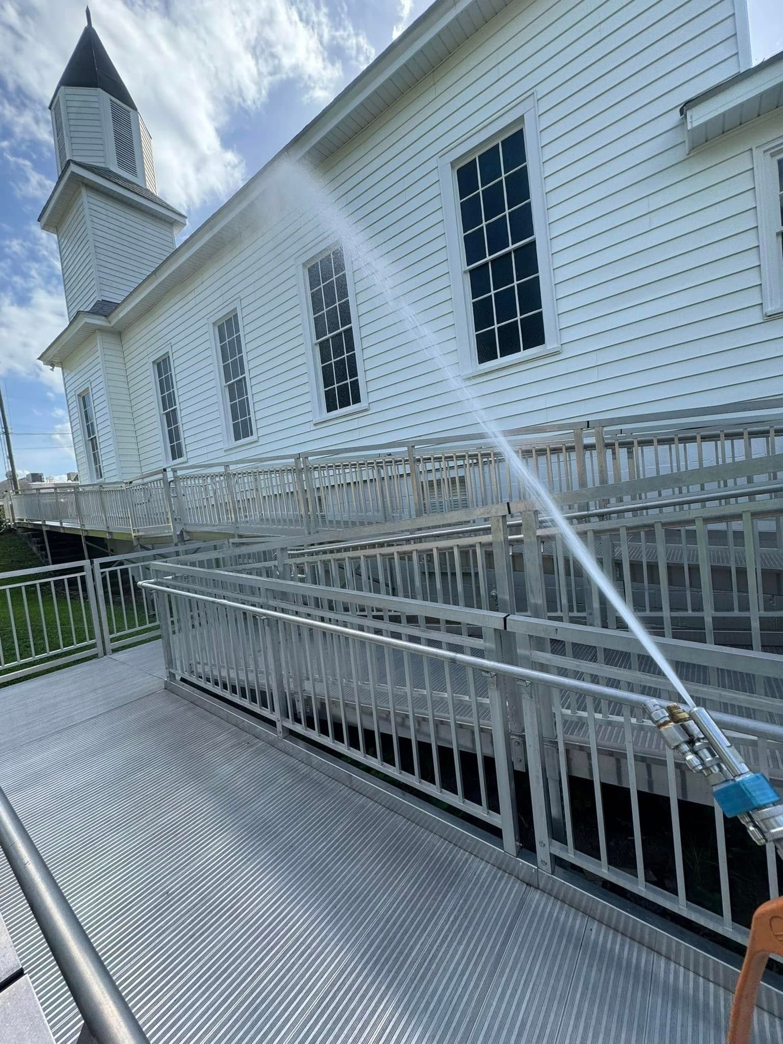Water spraying a metal ramp on a white church under a cloudy sky.