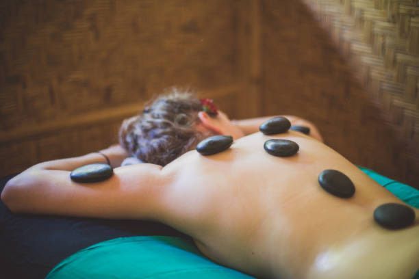 A woman is getting a massage with hot rocks on her back.