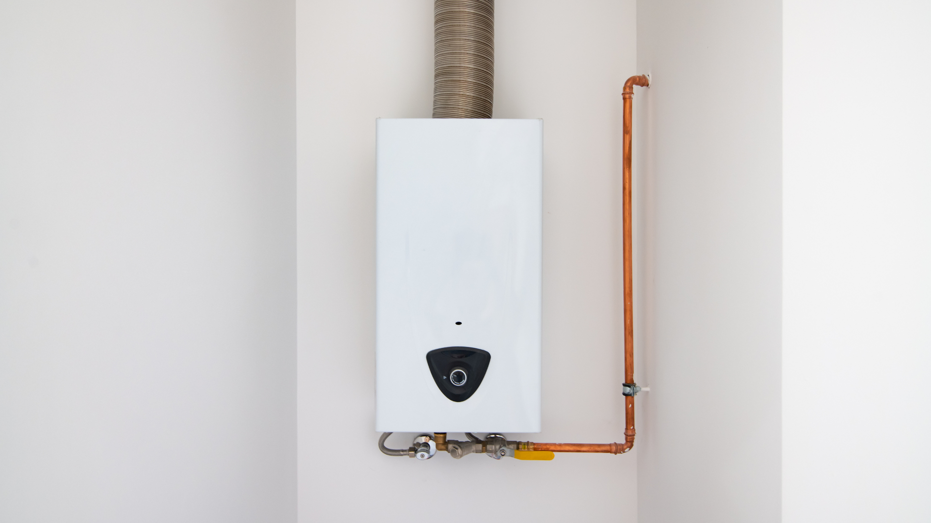 A white water heater is hanging on a white wall