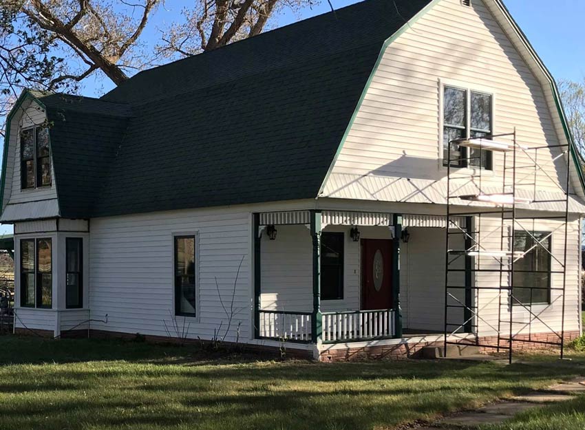 a white house with a green roof is having their windows serviced by Sun Glass