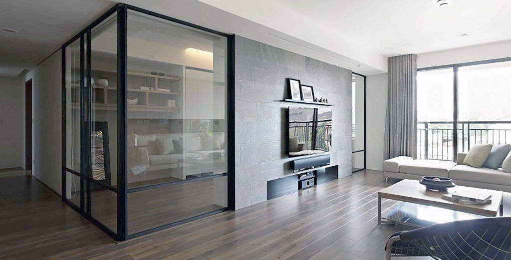 a living room with a glass wall installed by Sun Glass with a flat screen tv mounted on the wall