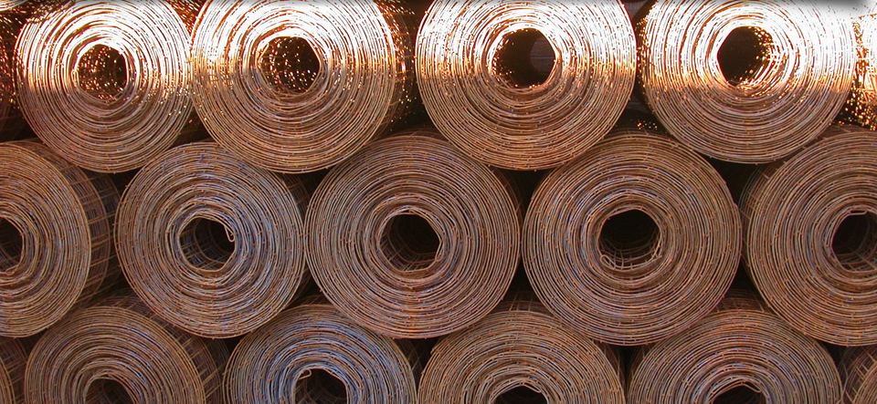 A bunch of rolls of wire mesh are stacked on top of each other.