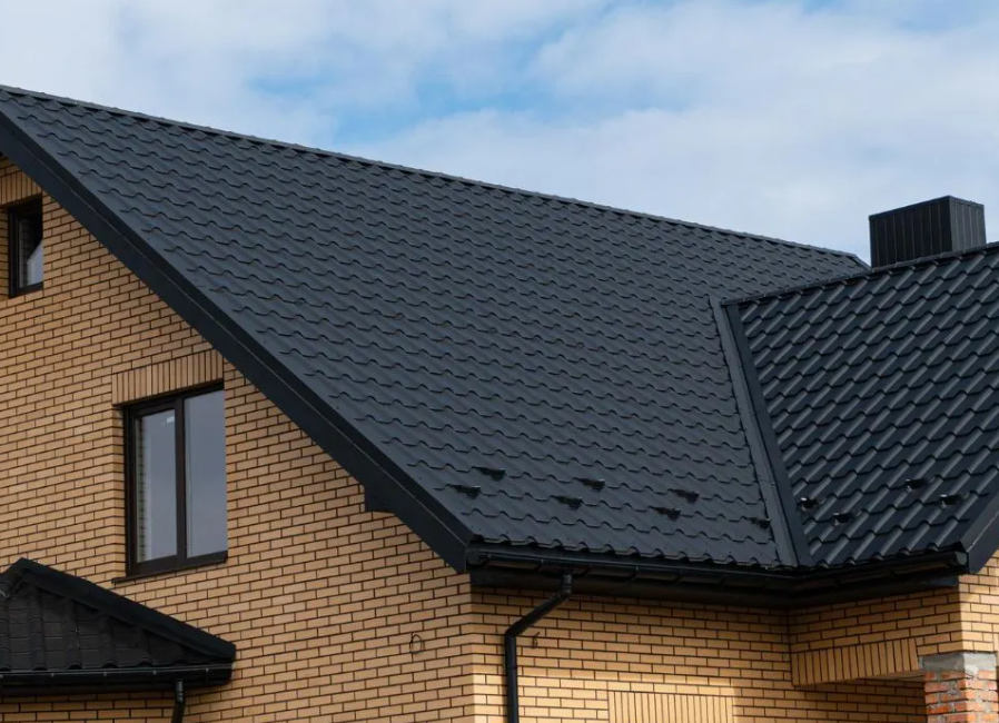 A brick house with a black roof and windows.