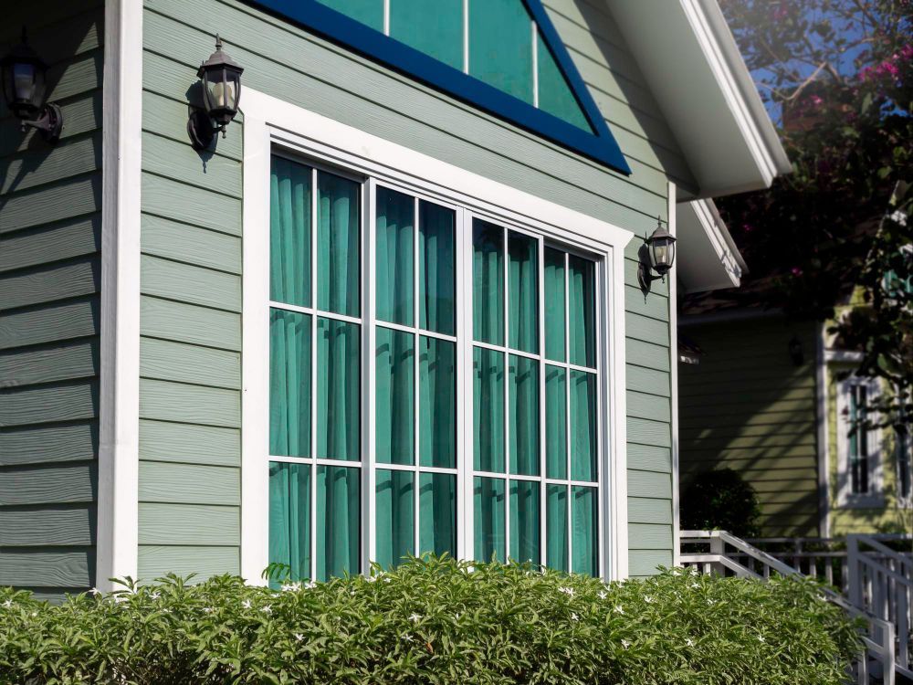 A green house with white trim and a large window