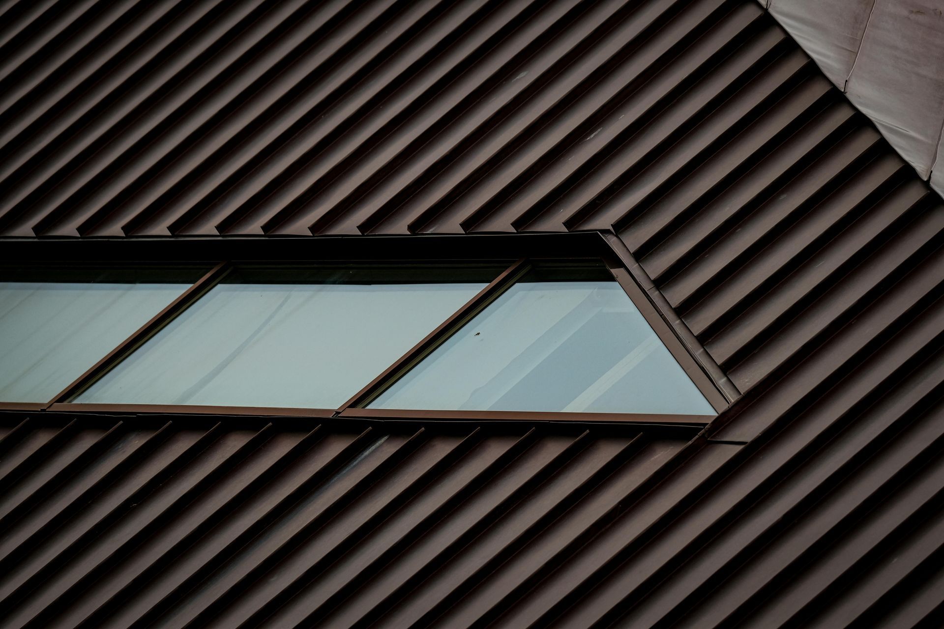 Triangular window with a dark brown, diagonally paneled exterior.