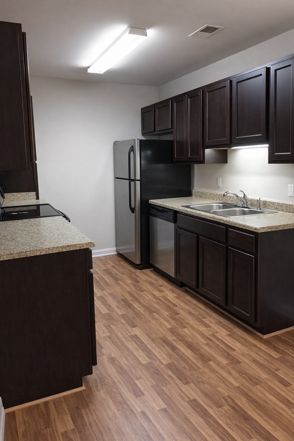 Kitchen with dark brown cabinets, stainless steel appliances, and wood-look flooring.