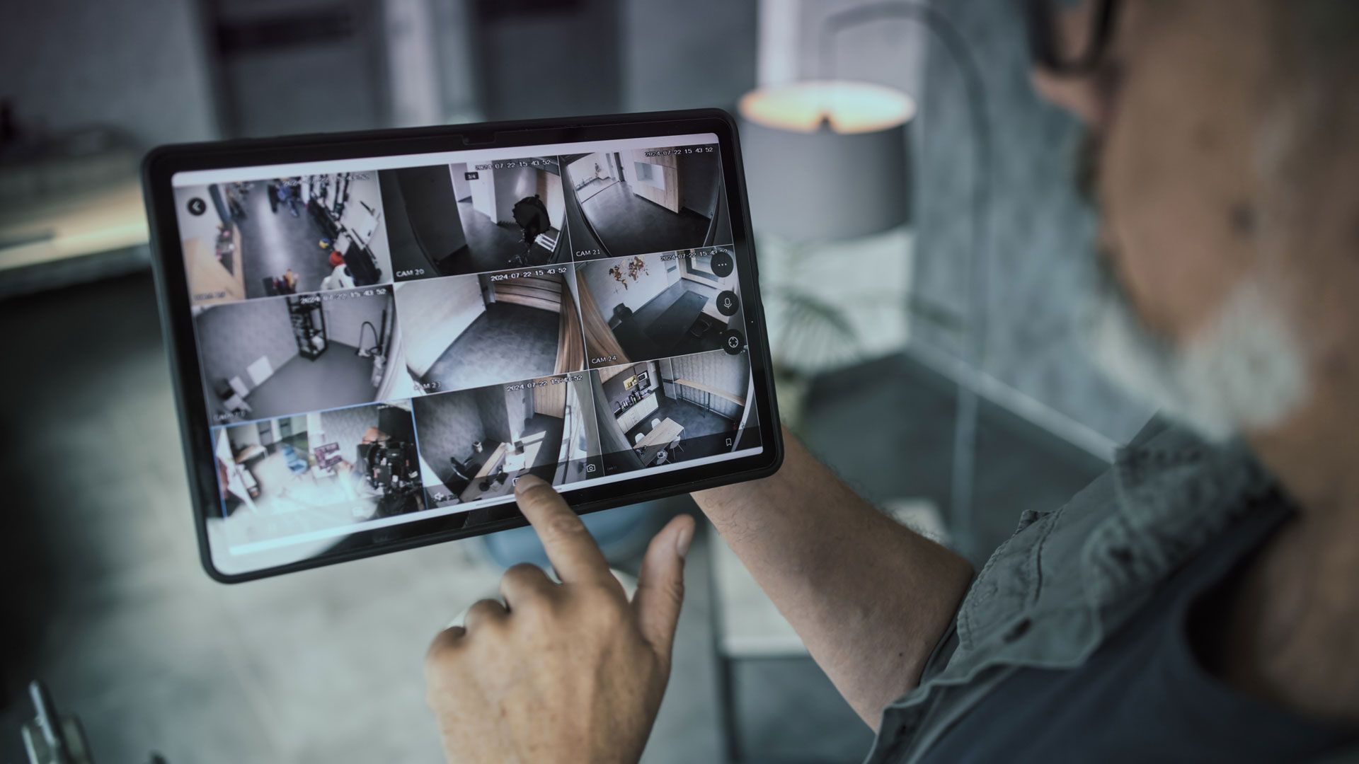Person viewing multiple security camera feeds on a tablet.