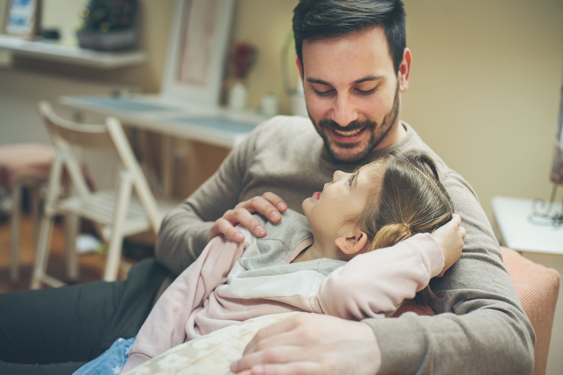 A man is sitting on a couch holding a little girl