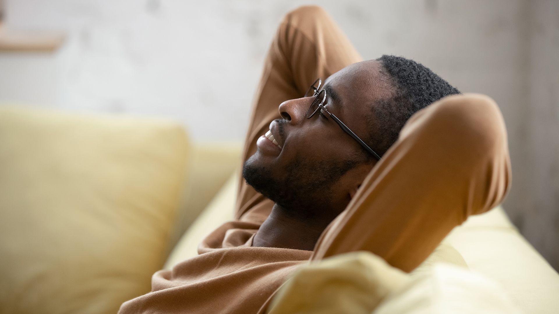 A man is sitting on a bean bag chair with his hands behind his head