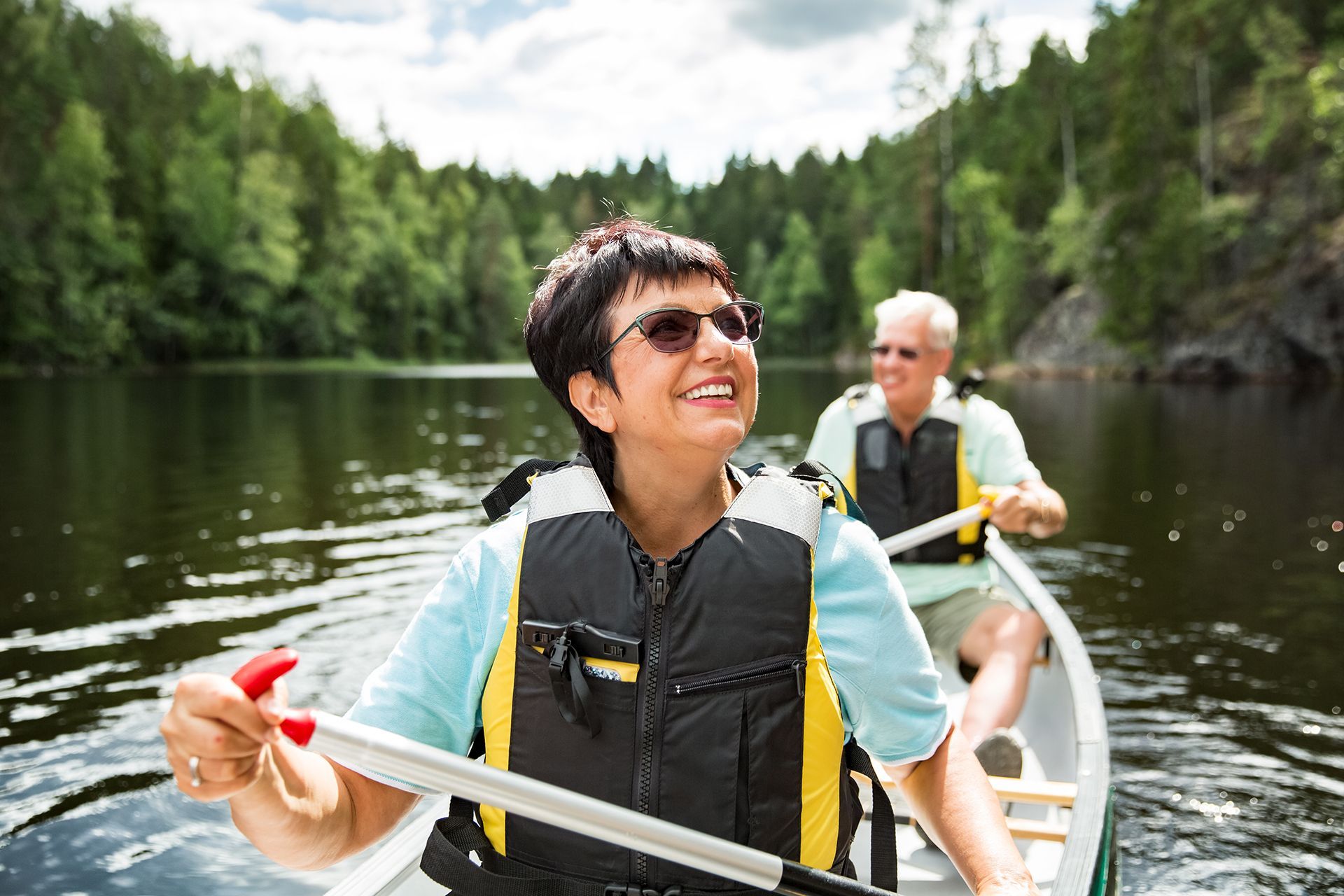 A man and a woman are paddling a canoe on a lake