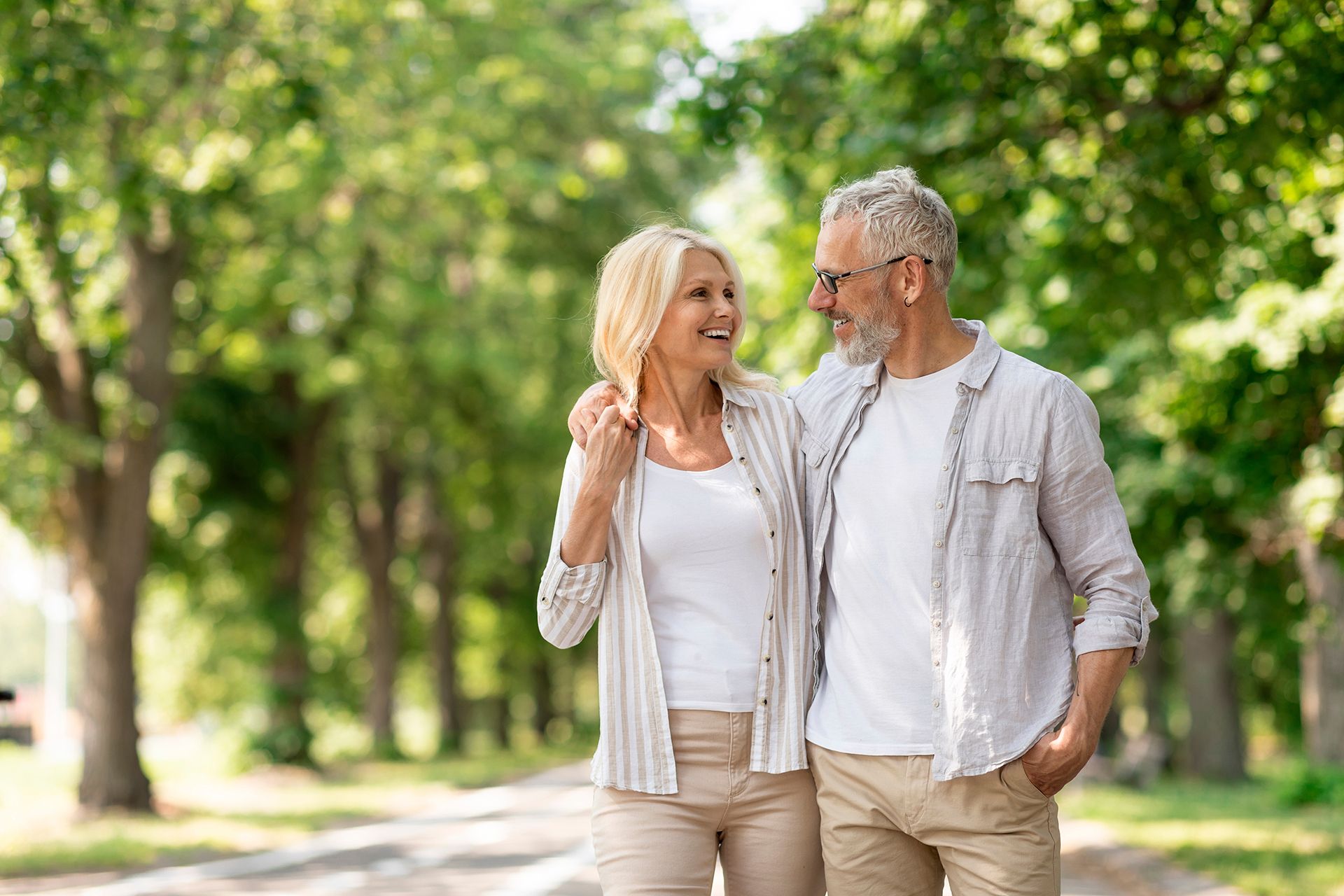 A man and a woman are walking down a path in a park