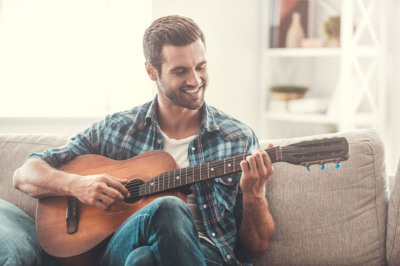 A man is sitting on a couch playing a guitar