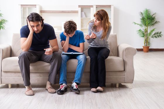 A family is sitting on a couch looking at a tablet.