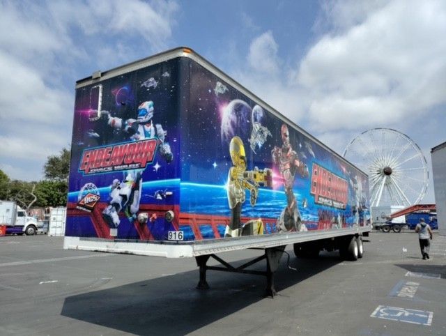 Large trailer with a space-themed mural and a Ferris wheel in the background.