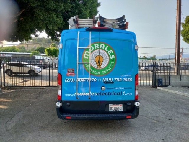 Blue Morales Electrical Services van with ladder, logo, and phone numbers.