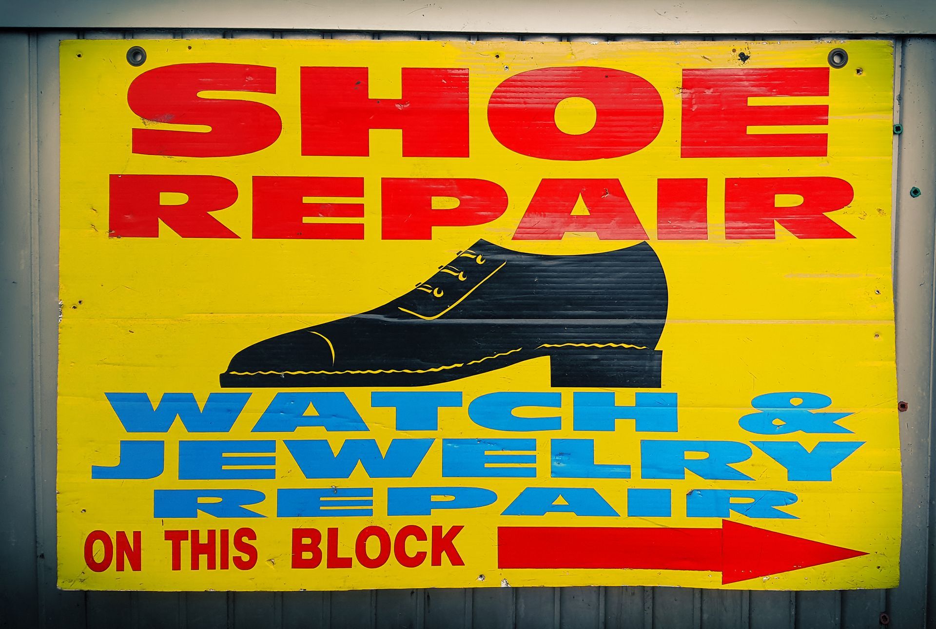 Sign for shoe, watch, and jewelry repair, with shoe illustration and arrow.