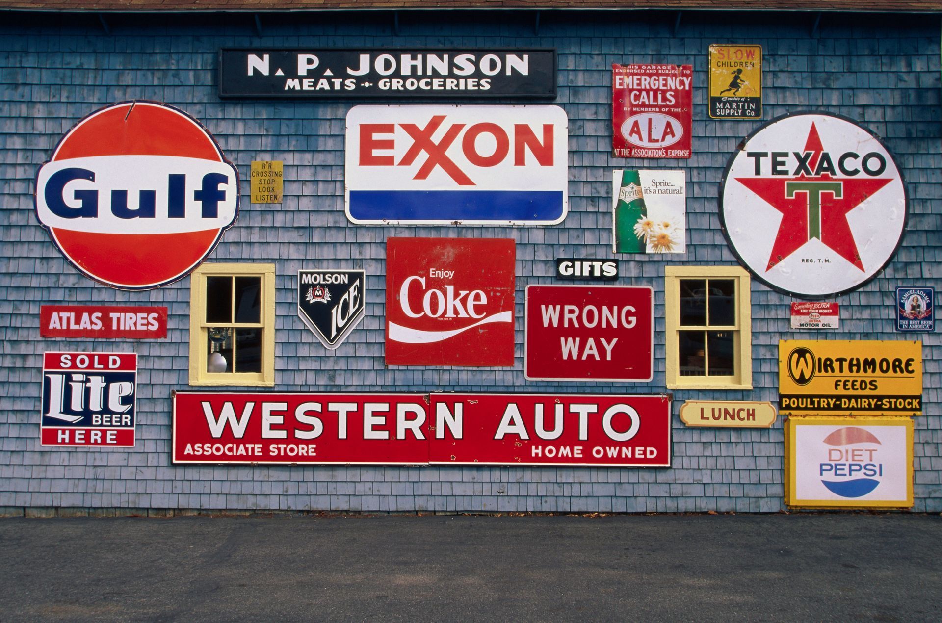 A wall covered in vintage signs for various businesses, including gas stations, food, and auto parts.