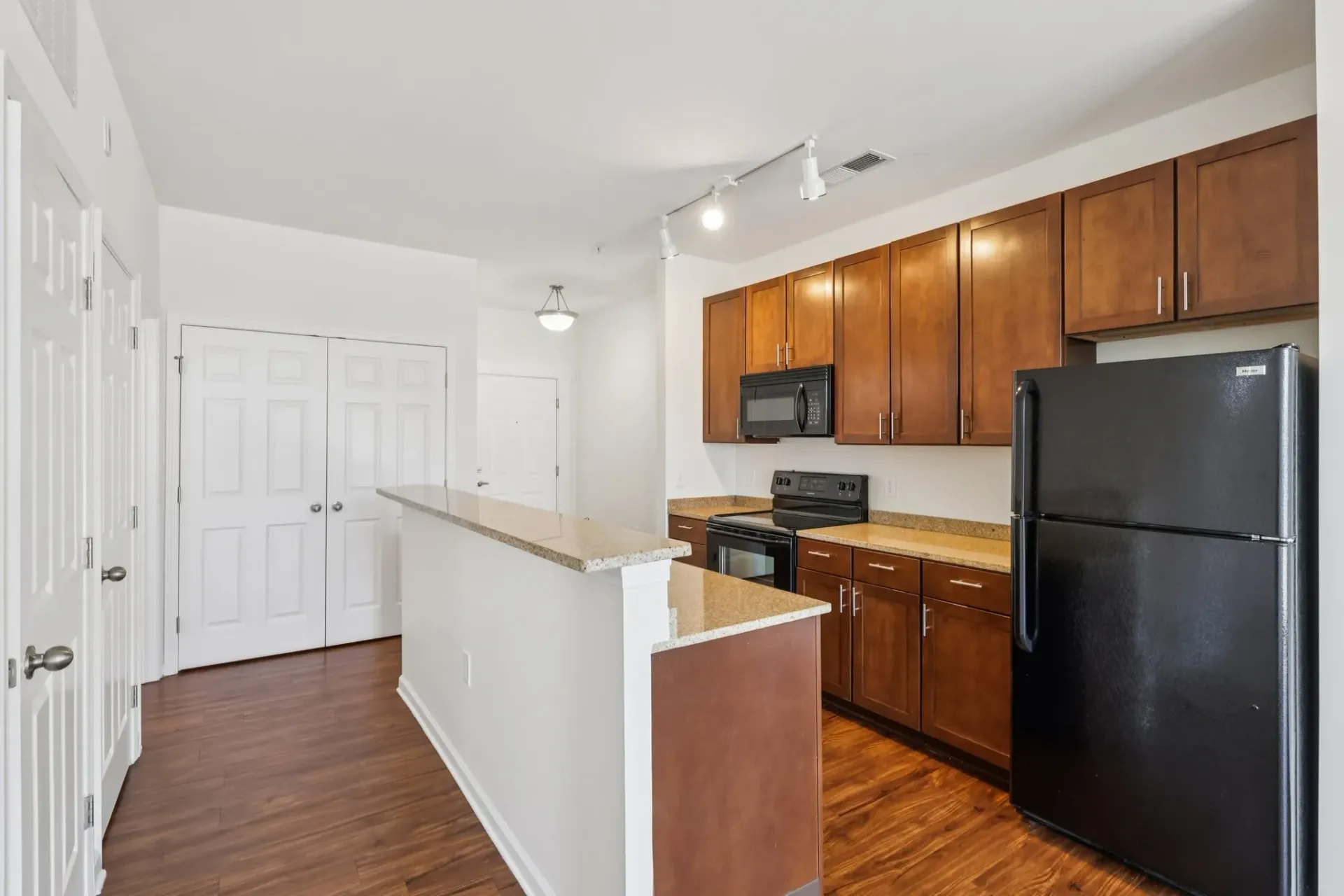 Modern kitchen with dark wood cabinets, granite countertops, stainless steel appliances, and a breakfast bar.